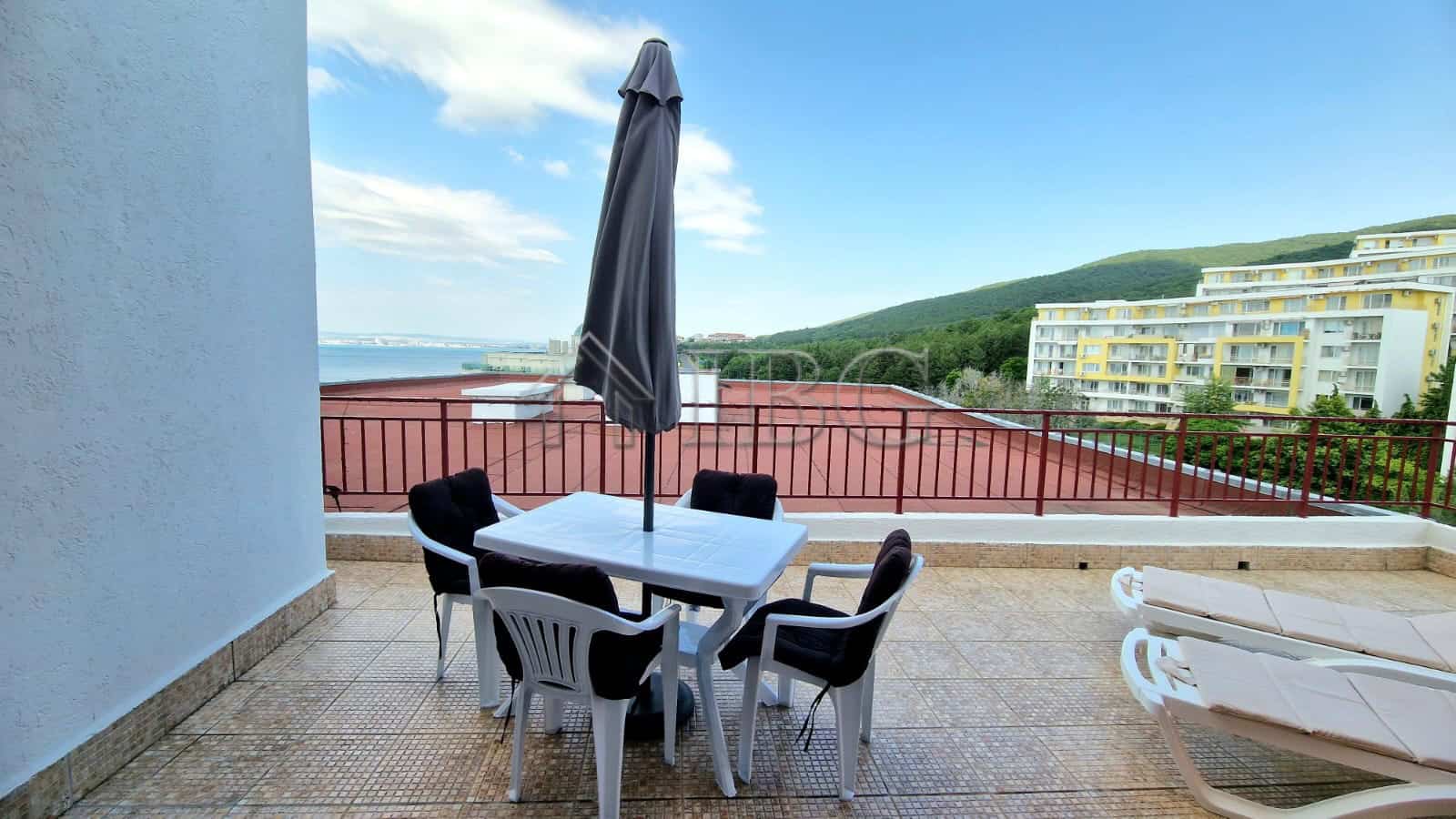 Outdoor terrace with sea view, table, chairs, and umbrella in Sveti Vlas.