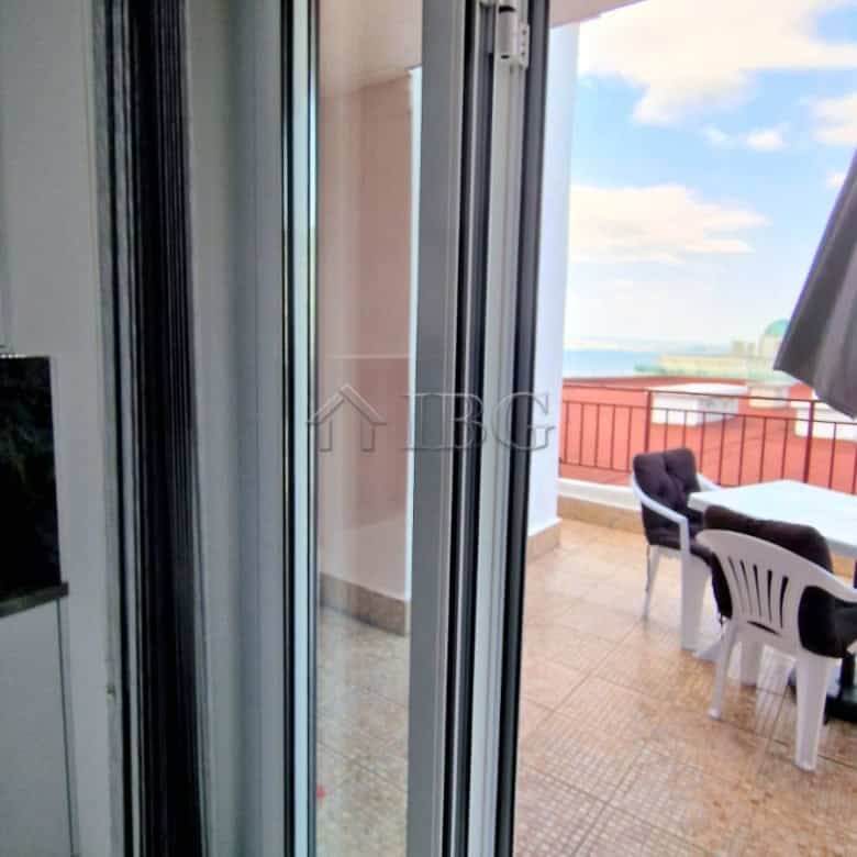 Balcony door opening to a spacious terrace with sea view and outdoor seating.