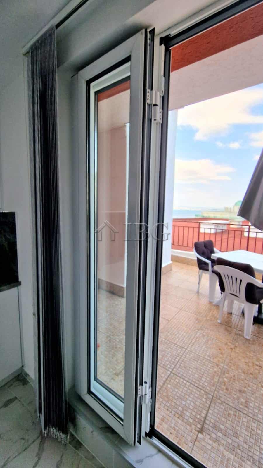 Balcony door opening to a spacious terrace with sea view and outdoor seating.