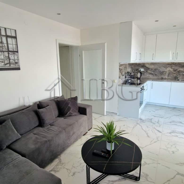 Bright living room with stylish decor, open-plan kitchen, and large windows overlooking the sea.