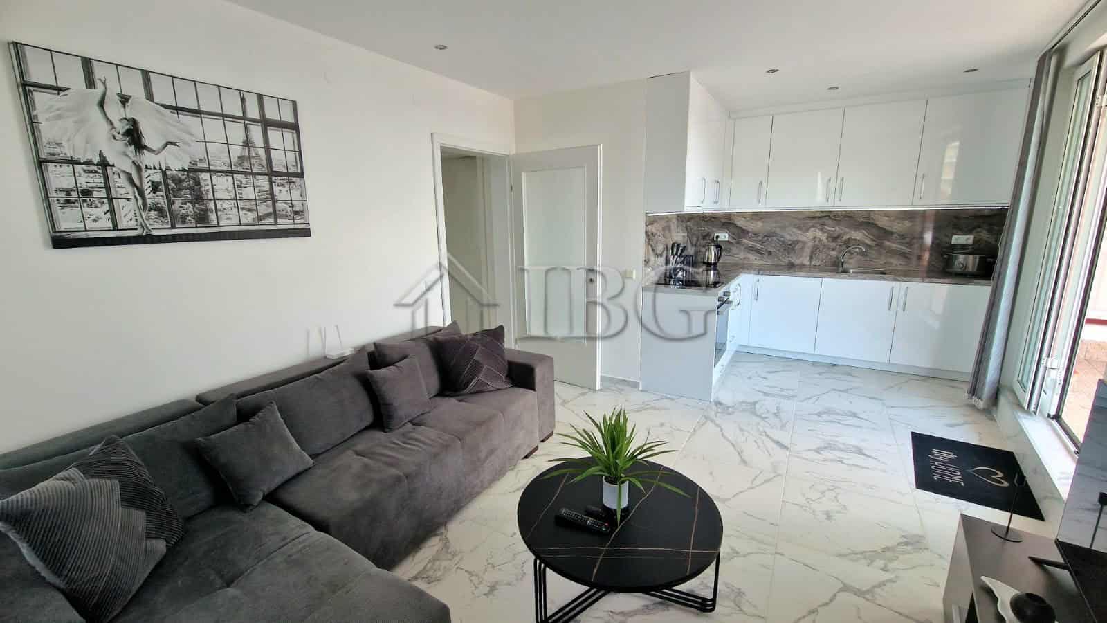 Bright living room with stylish decor, open-plan kitchen, and large windows overlooking the sea.