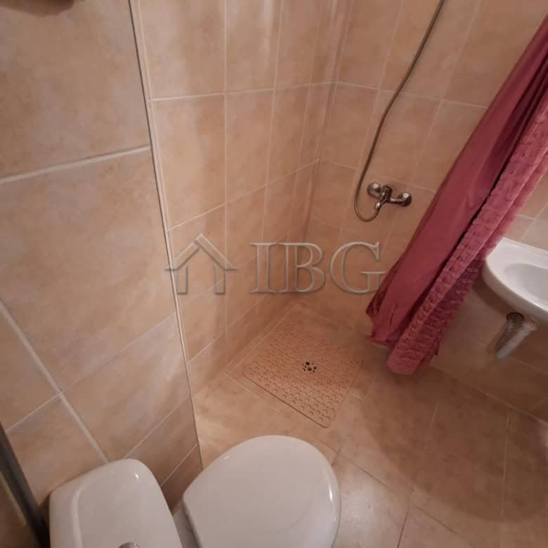 Compact bathroom with shower, toilet, and sink in a furnished studio apartment. Perfect for short st.