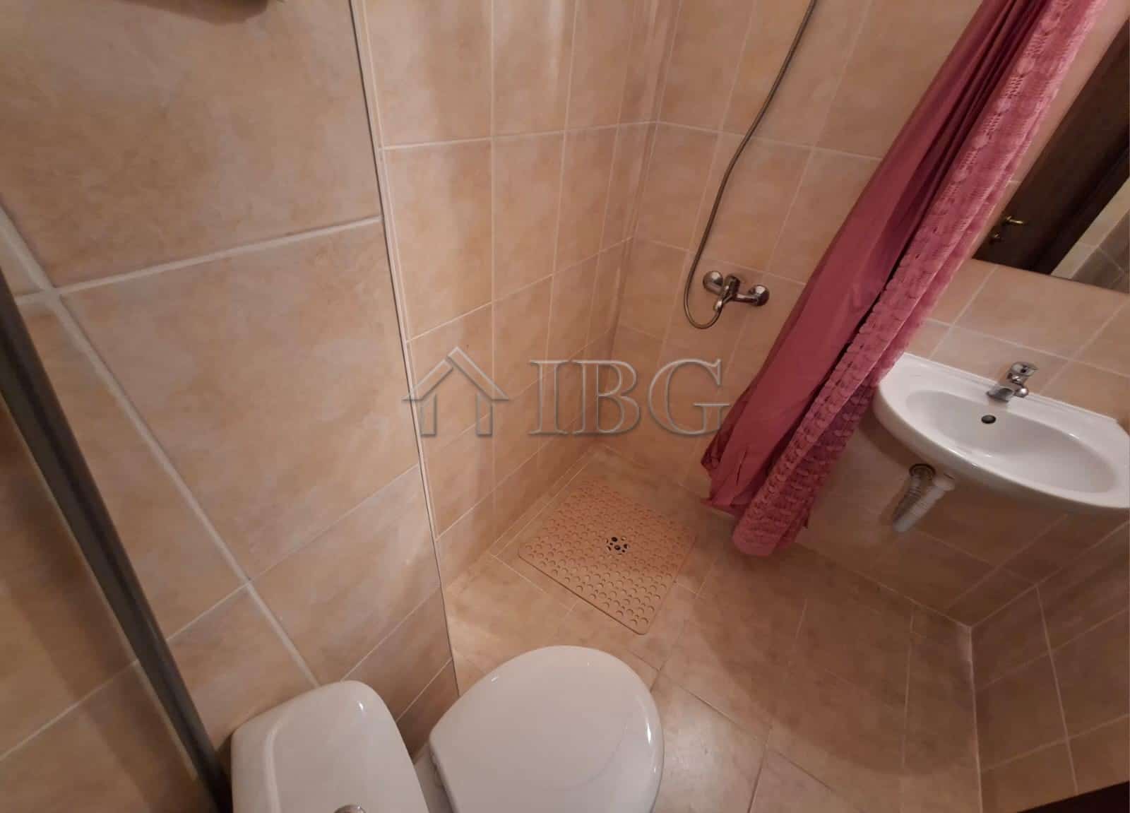 Compact bathroom with shower, toilet, and sink in a furnished studio apartment. Perfect for short st.