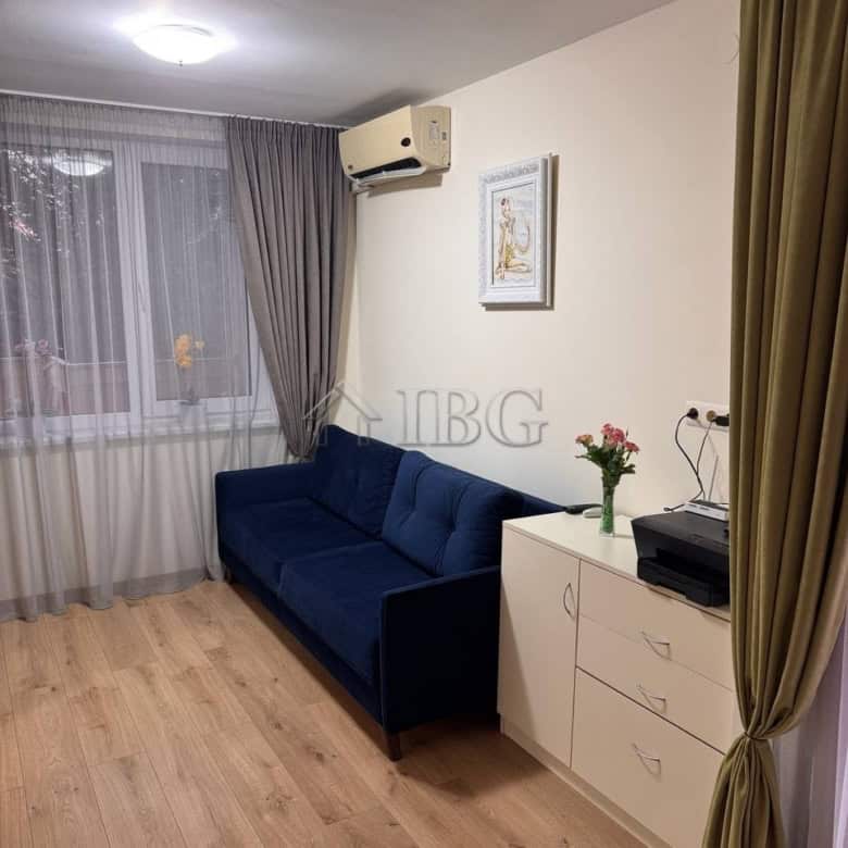 Bright living room with a blue sofa and large window with curtains.