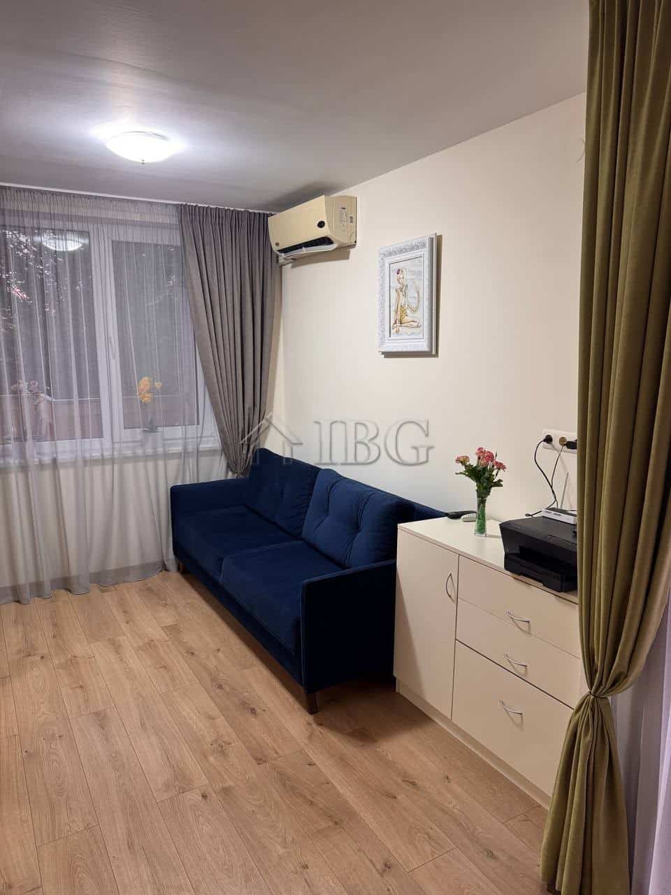 Bright living room with a blue sofa and large window with curtains.