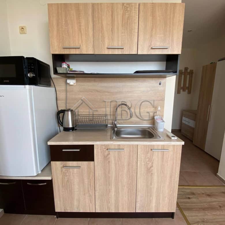 Compact studio kitchen with sea view, microwave, and fridge at Crown Fort Club.