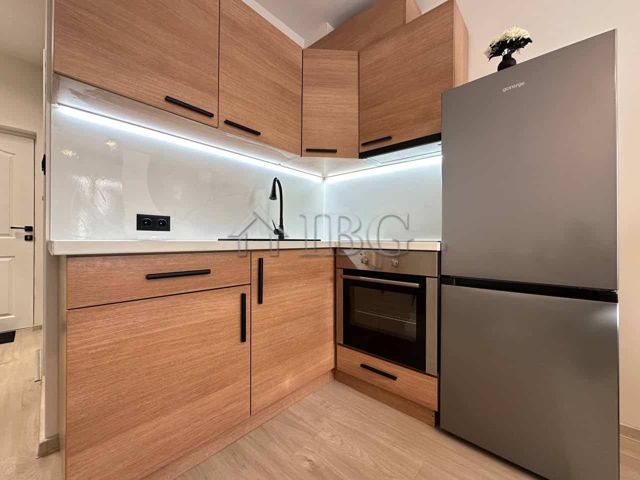 Compact kitchen with wooden cabinets, stainless steel fridge, and modern appliances in Sveti Vlas.