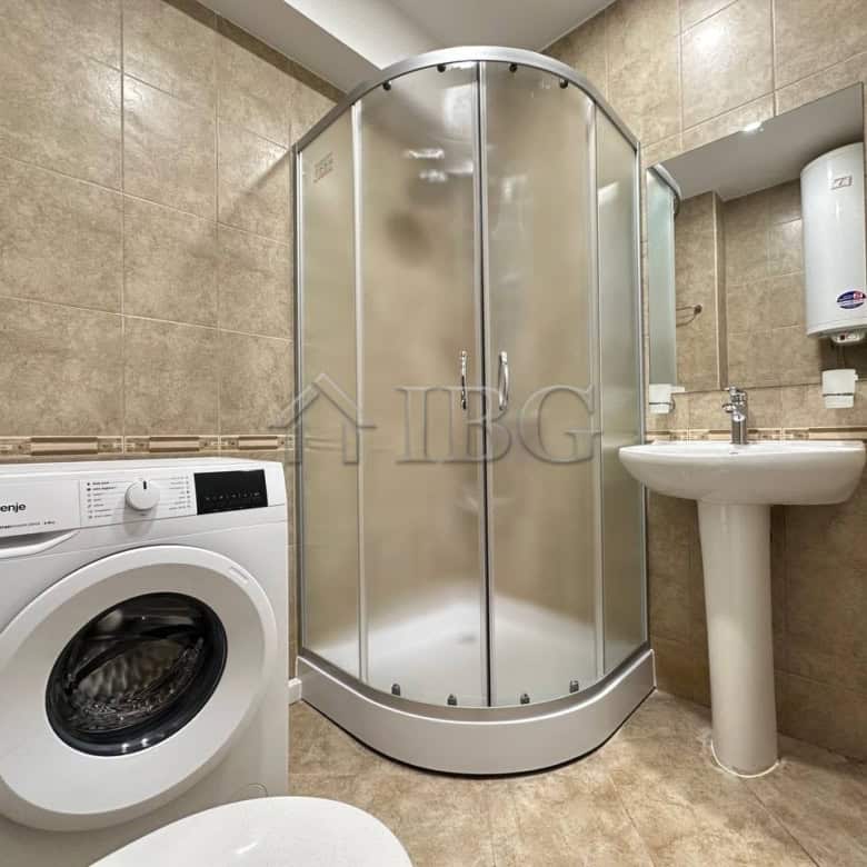 Compact bathroom with shower, washing machine, and sink in Sveti Vlas.