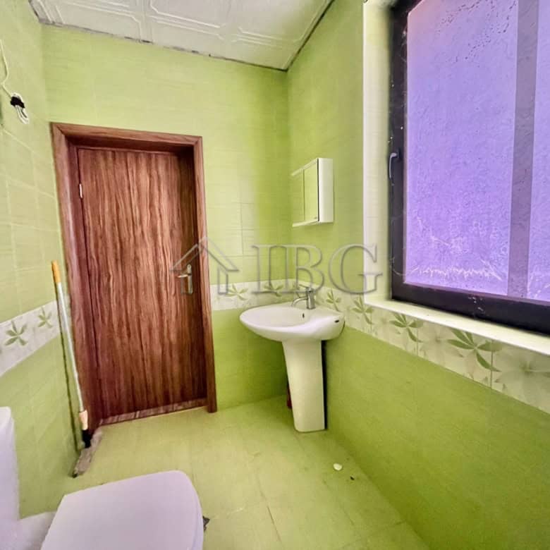 Bright bathroom with green walls, window, and white fixtures in Goritsa Village.