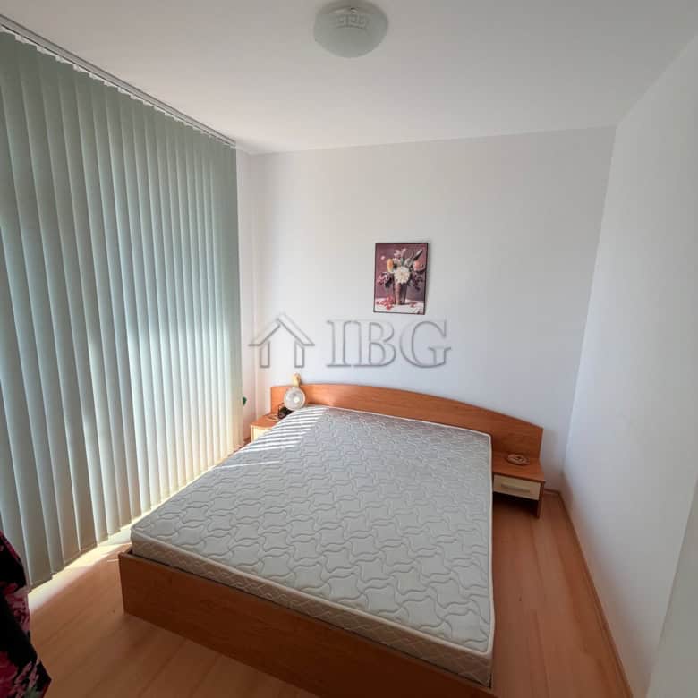 Bright bedroom with large window, minimalist decor, and wooden furniture in Sunny Beach apartment.
