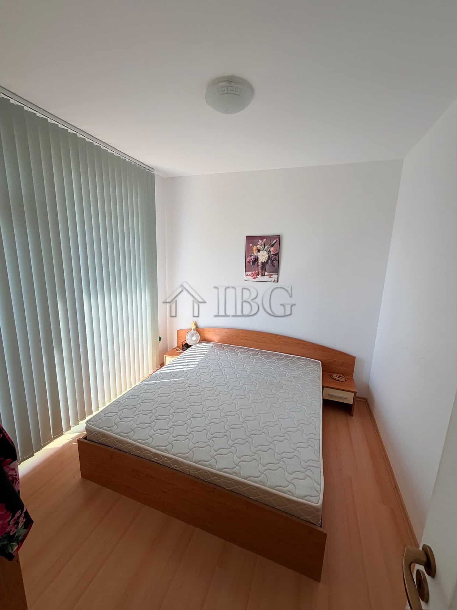 Bright bedroom with large window, minimalist decor, and wooden furniture in Sunny Beach apartment.