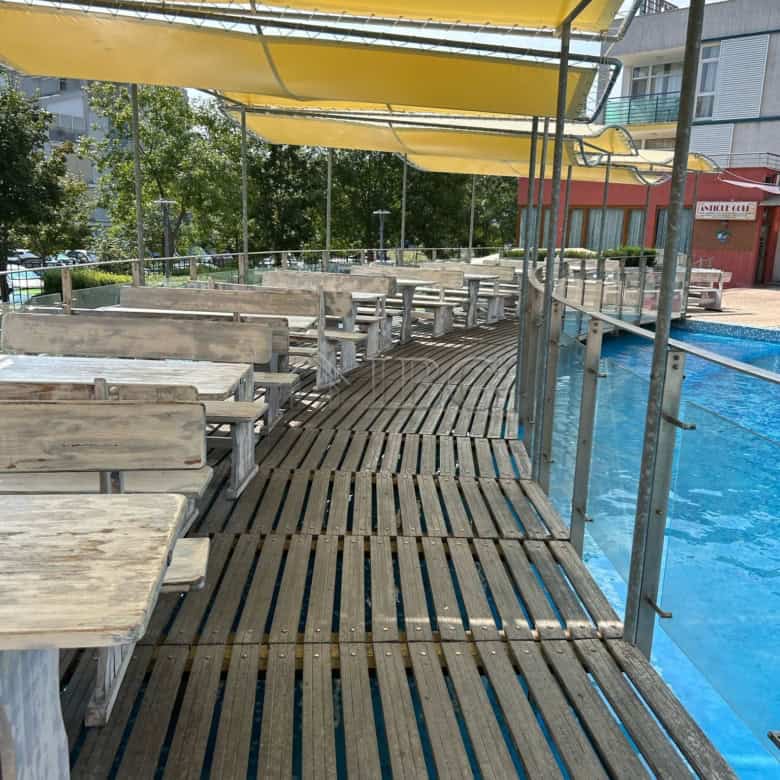 Poolside wooden deck with sunshade and seating area at a beachfront property.