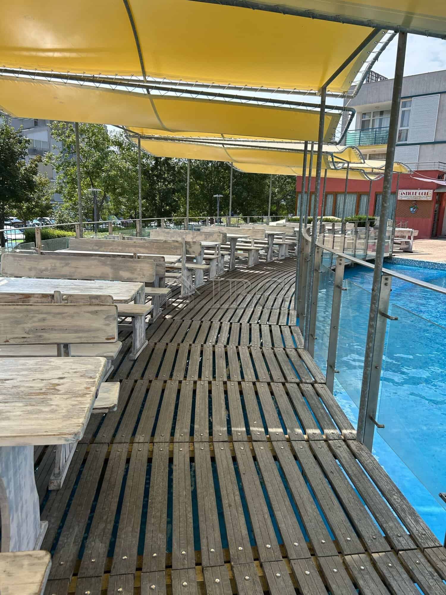Poolside wooden deck with sunshade and seating area at a beachfront property.