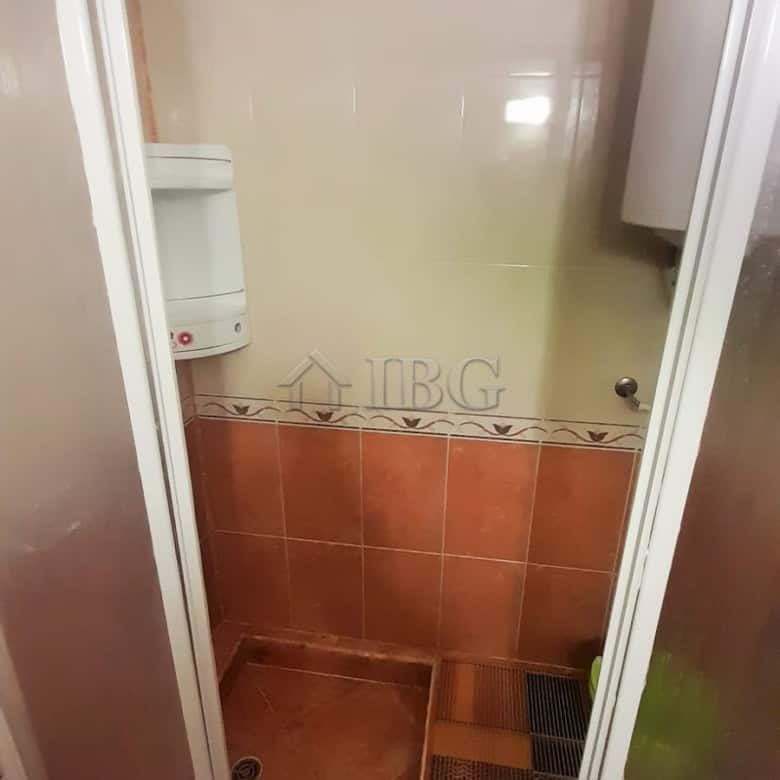 Shower stall with glass door and tiled interior in a small bathroom setting.