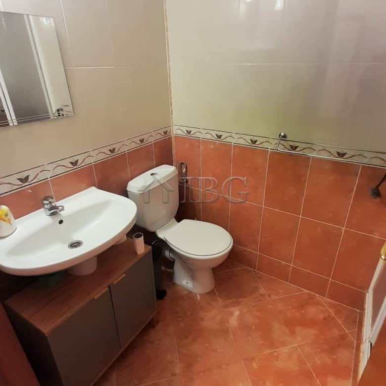 Bathroom with sink, toilet, and tiled walls in a modern apartment.