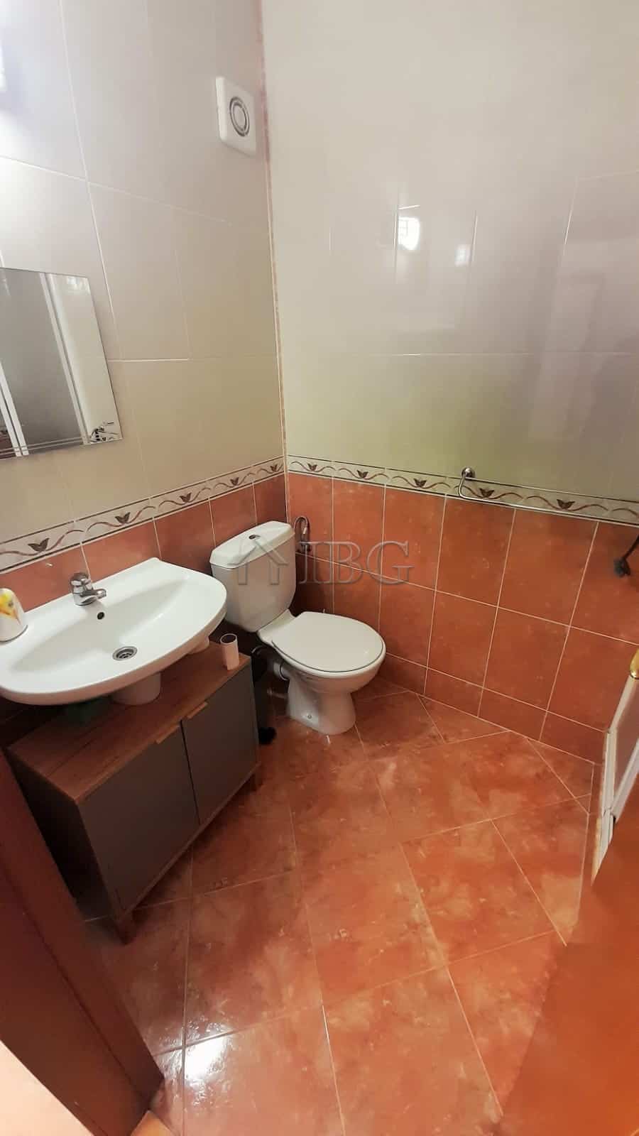 Bathroom with sink, toilet, and tiled walls in a modern apartment.