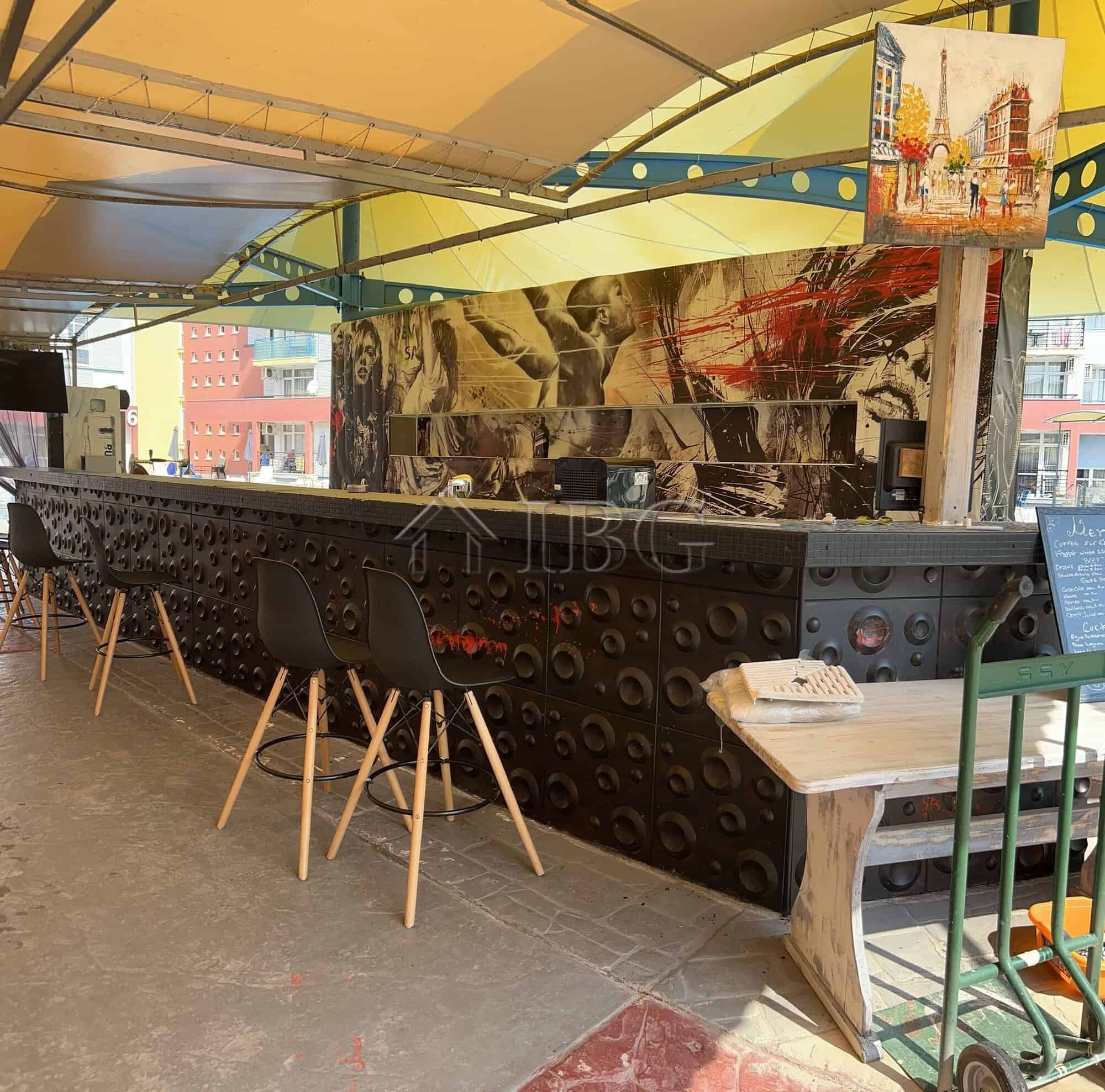 Bar counter with artistic mural and seating area at Sunny Beach, Cacao Beach.