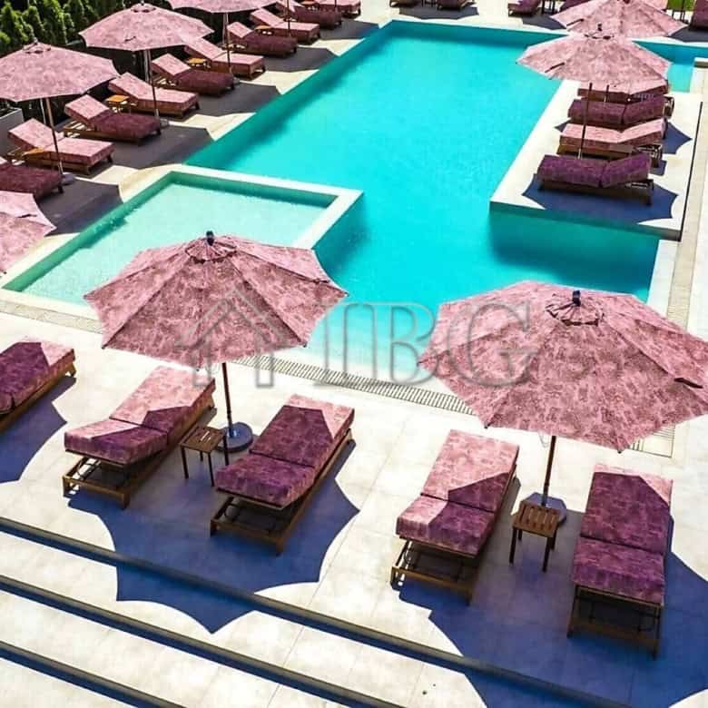Pool area with pink sun loungers and umbrellas in a contemporary resort setting.