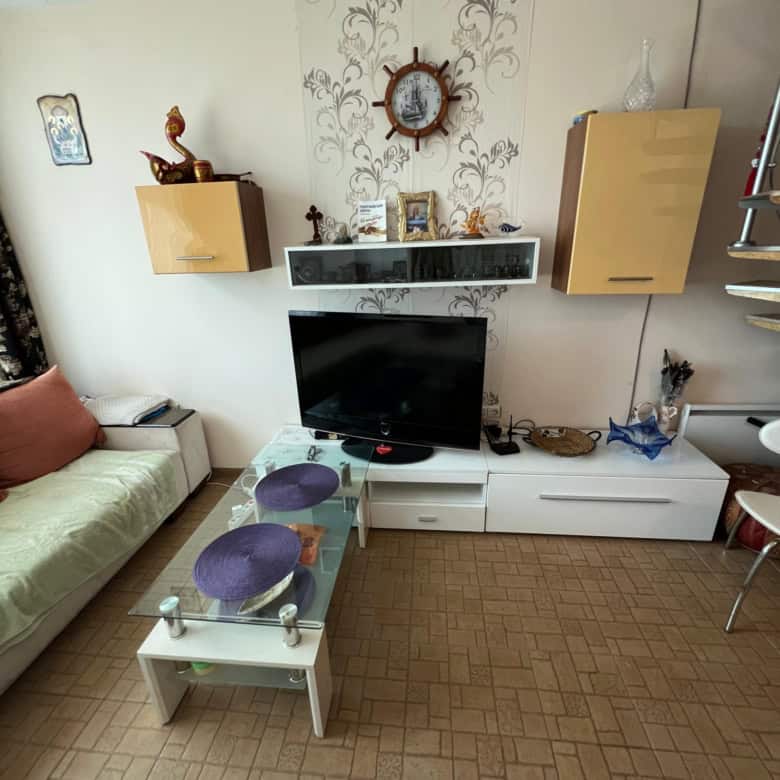 Cozy living room with TV, sofa, and decorative wall clock in Sunny Beach.