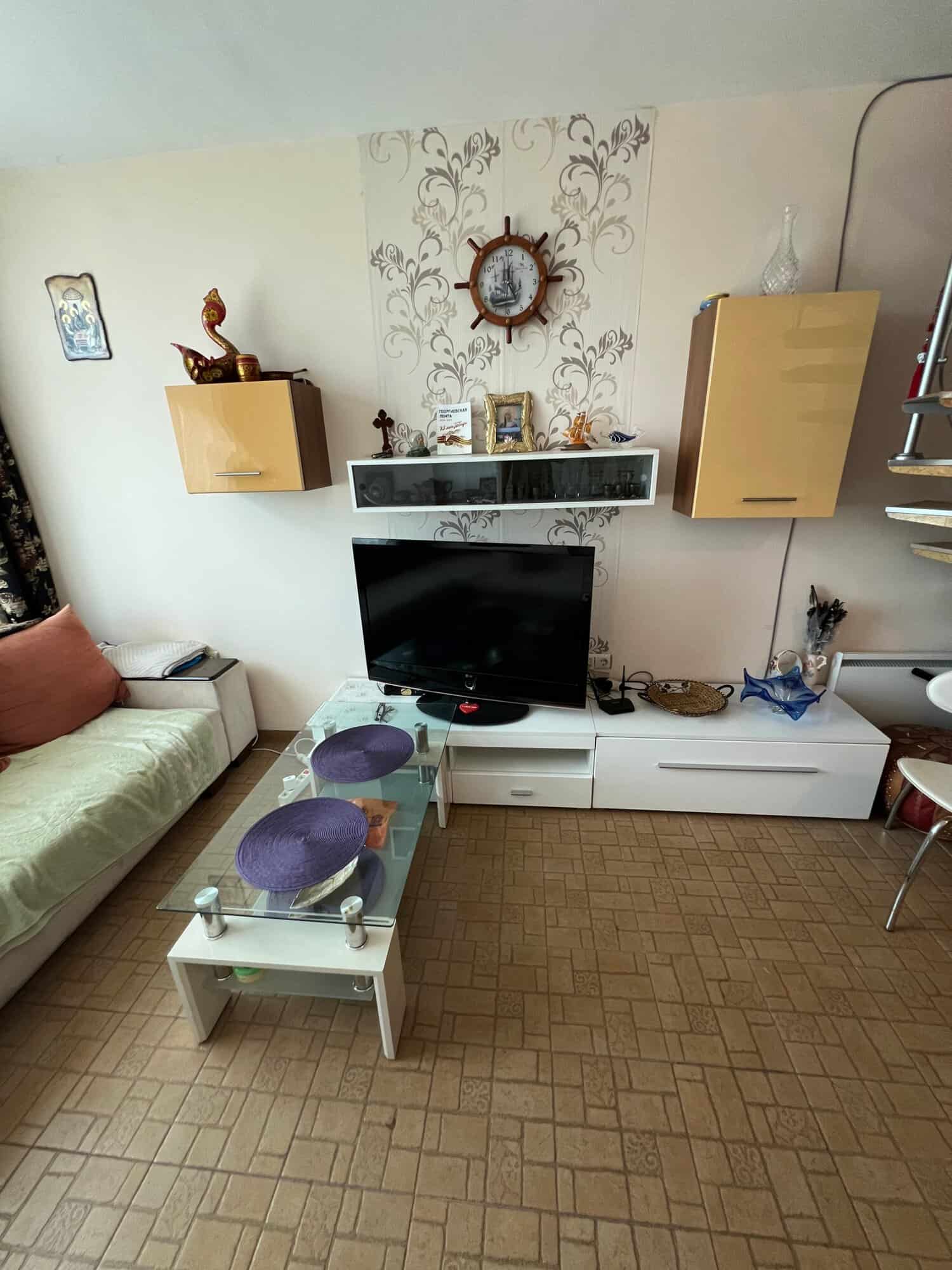 Cozy living room with TV, sofa, and decorative wall clock in Sunny Beach.