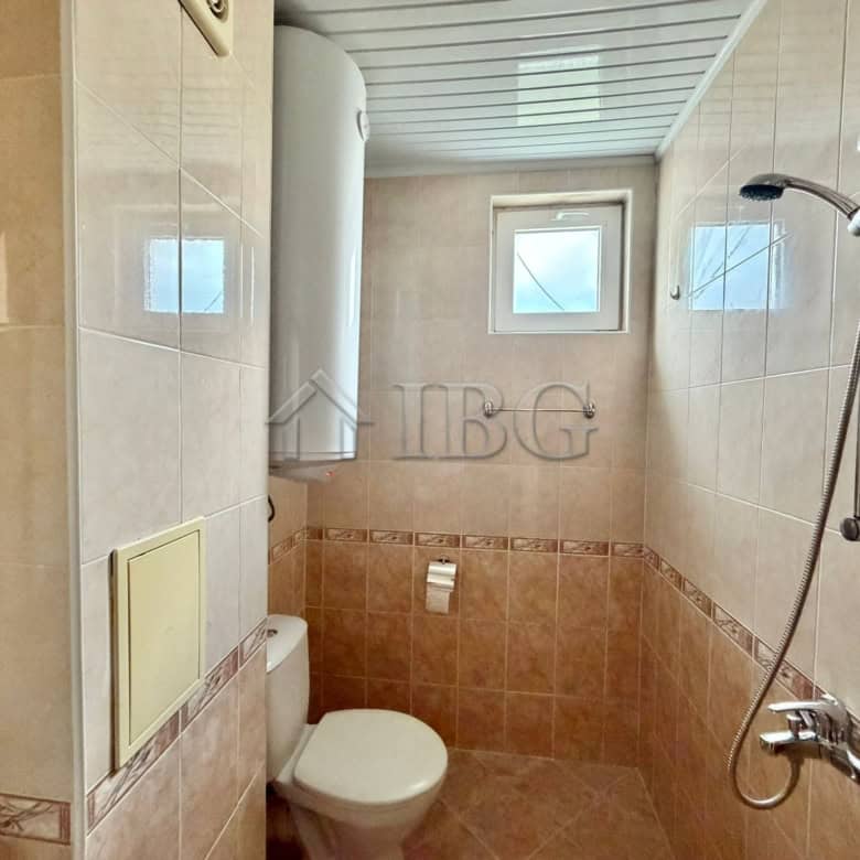 Bathroom with toilet and shower in a sunny beach apartment.