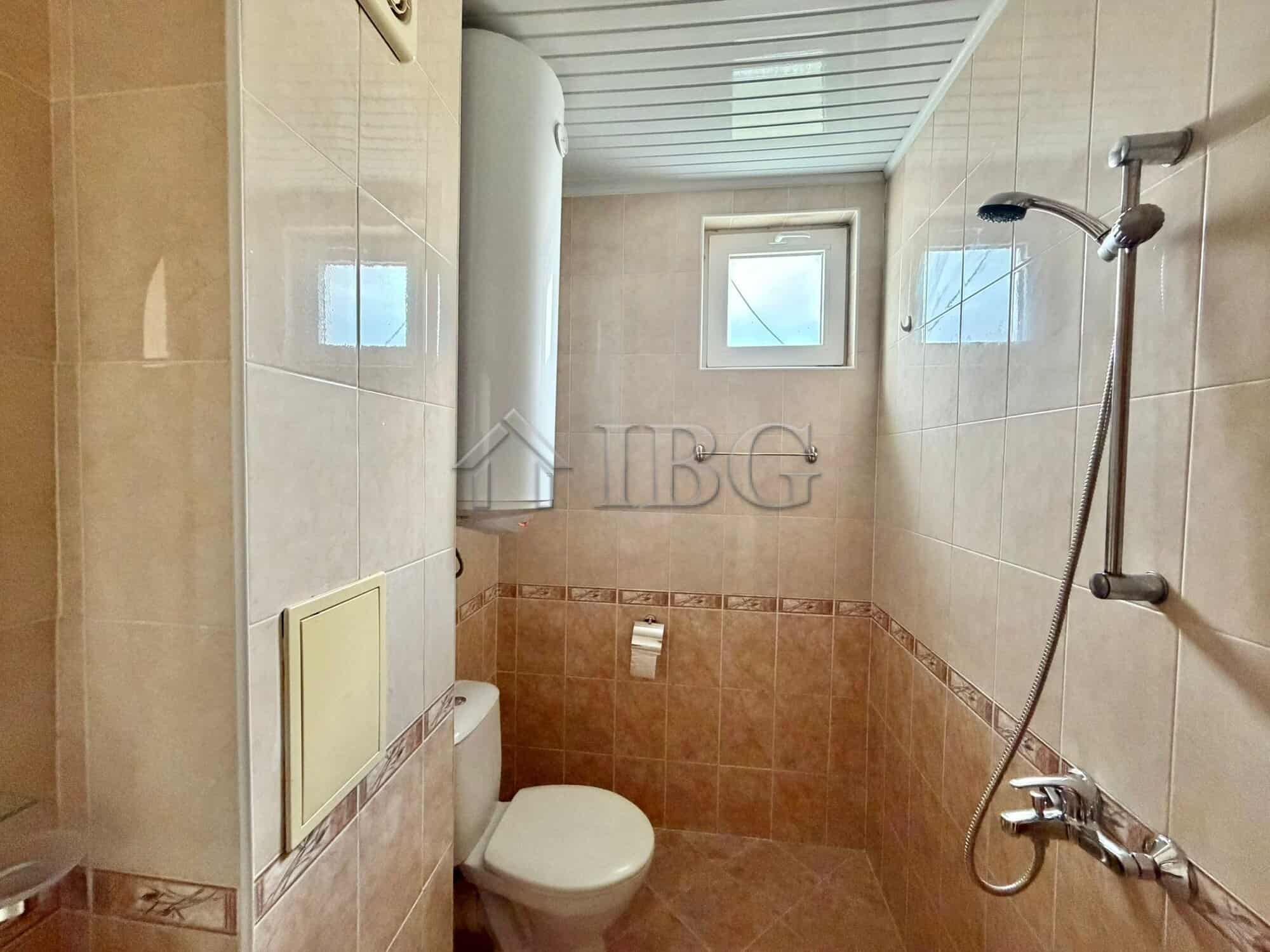 Bathroom with toilet and shower in a sunny beach apartment.