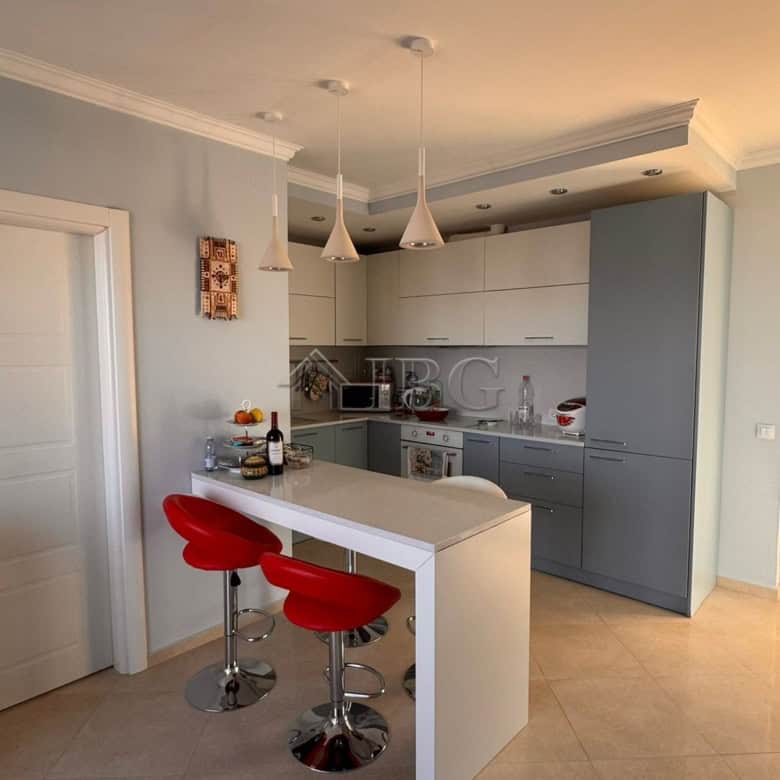Contemporary kitchen with white cabinets and red bar stools in Sveti Vlas apartment.