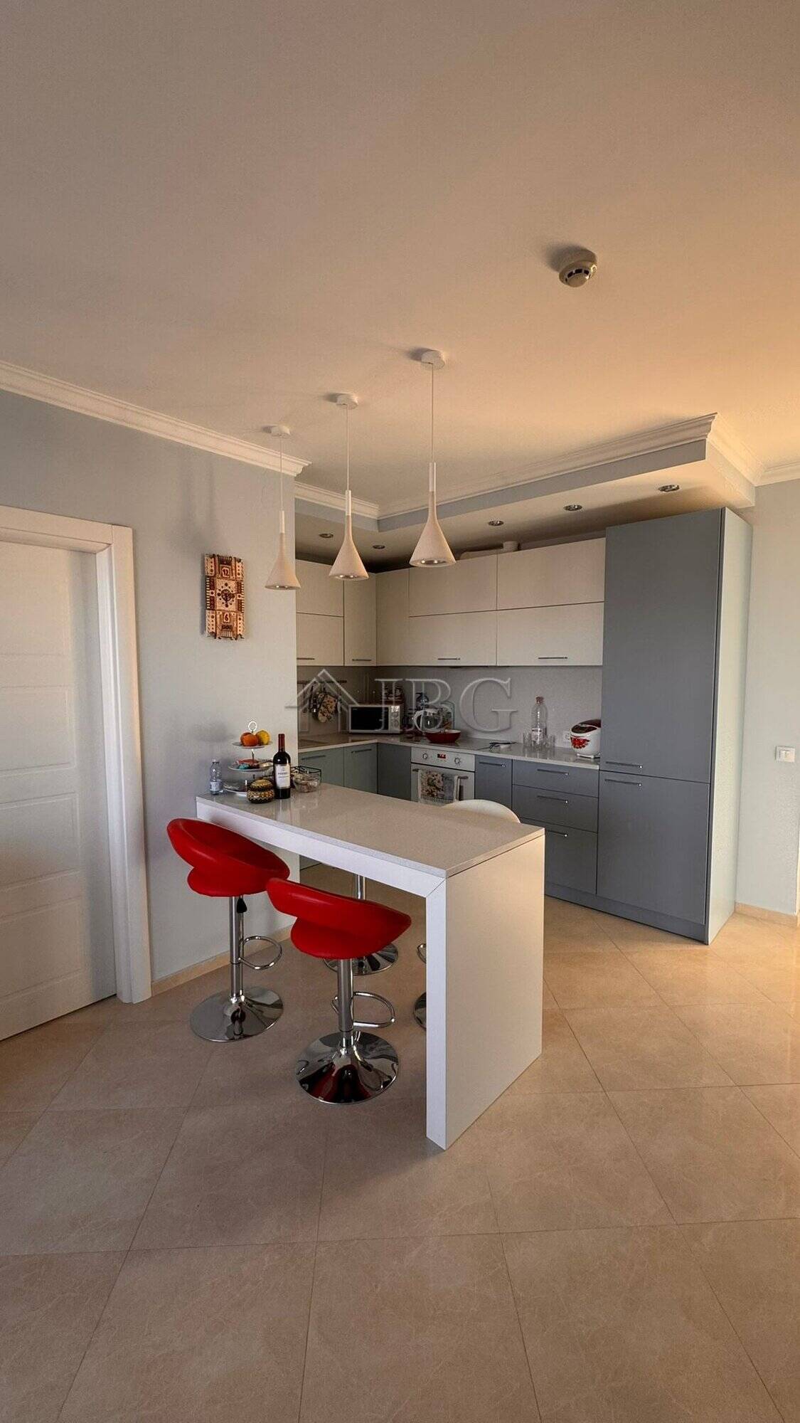 Contemporary kitchen with white cabinets and red bar stools in Sveti Vlas apartment.