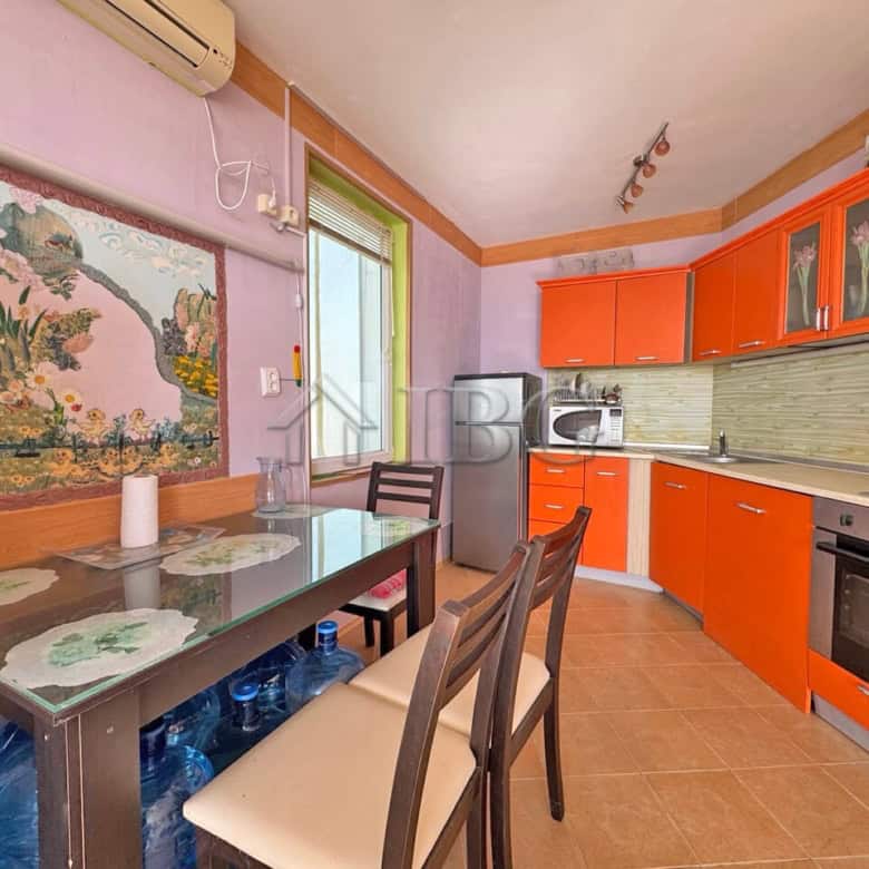 Bright kitchen with orange cabinets and sea view window.