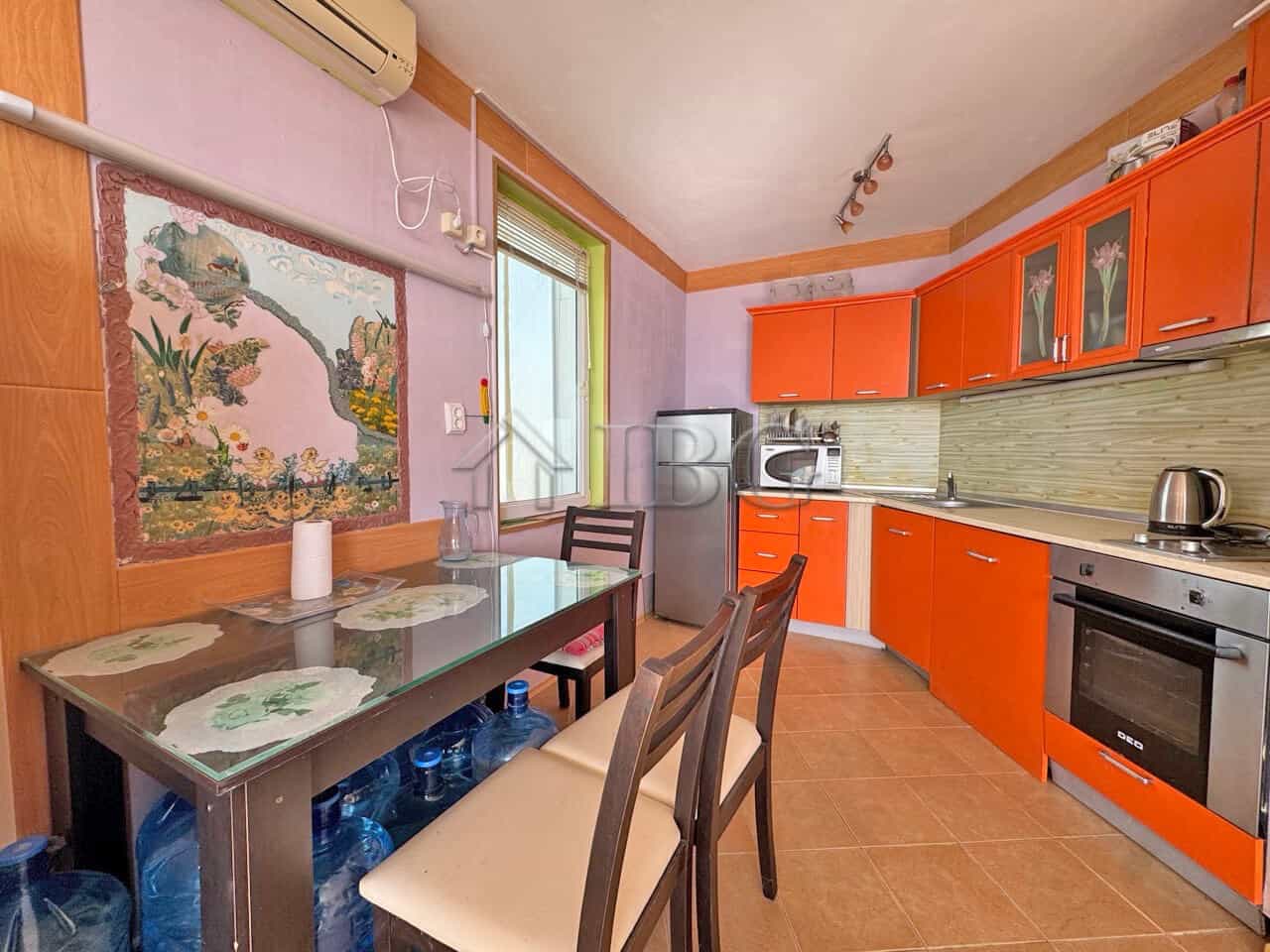 Bright kitchen with orange cabinets and sea view window.