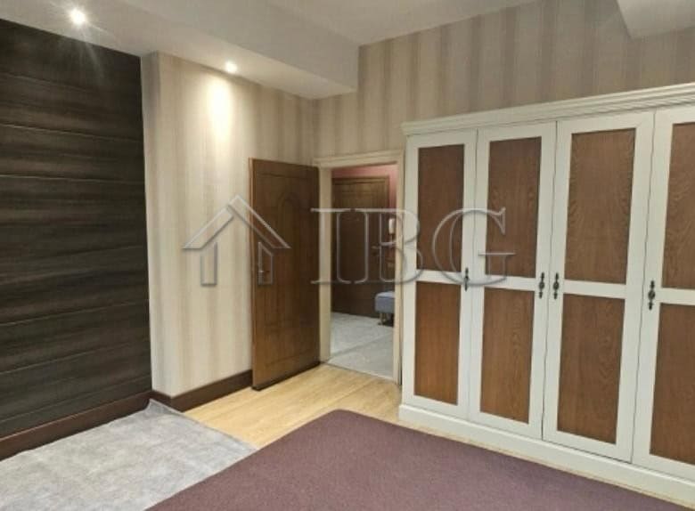 Bedroom with large white wardrobe and wooden wall paneling.