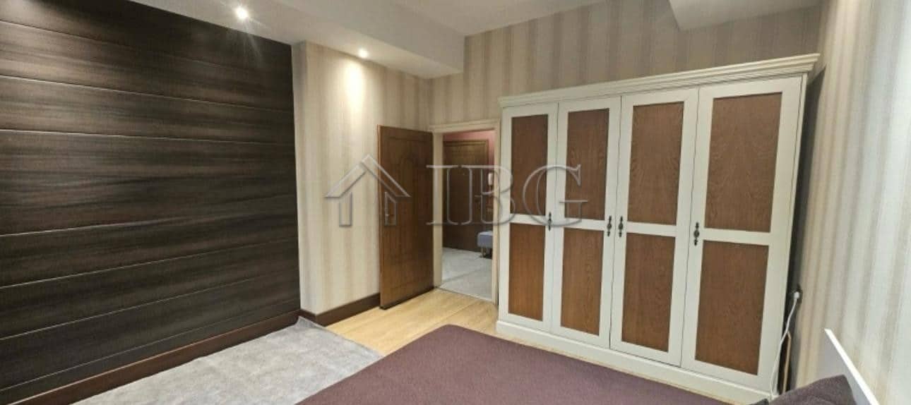 Bedroom with large white wardrobe and wooden wall paneling.