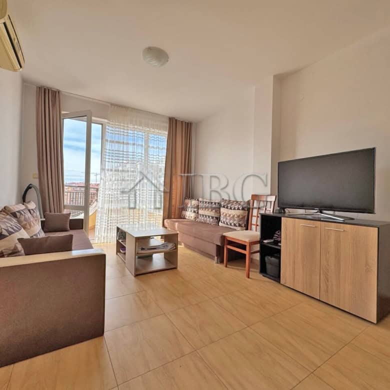 Cozy living room in Aqua Dreams apartment with modern furniture, large TV, and balcony with sea view.
