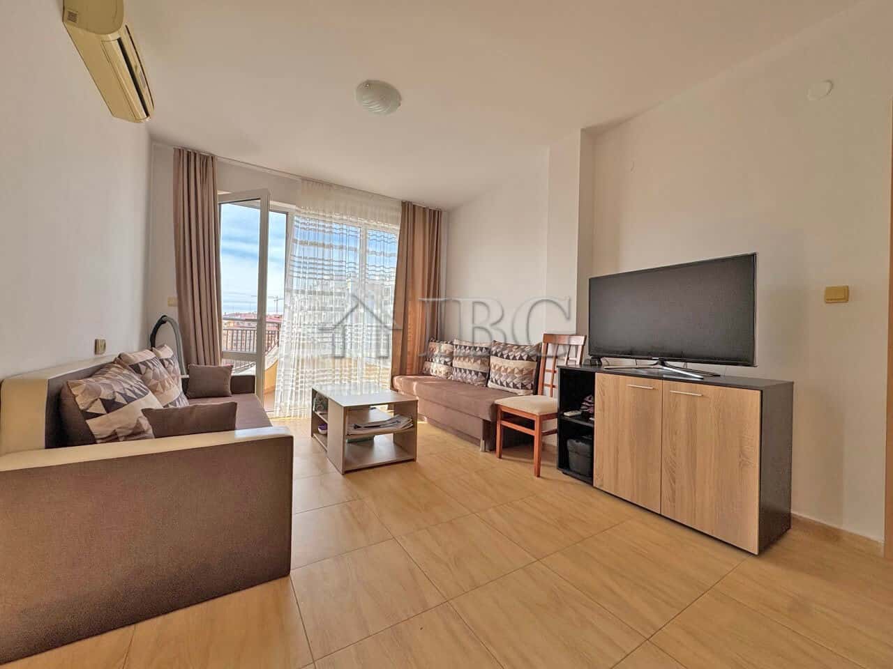 Cozy living room in Aqua Dreams apartment with modern furniture, large TV, and balcony with sea view.