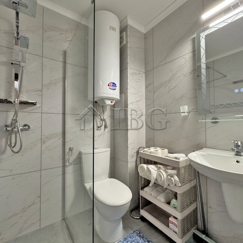 Bathroom with shower, toilet, and water heater in a spacious studio apartment.