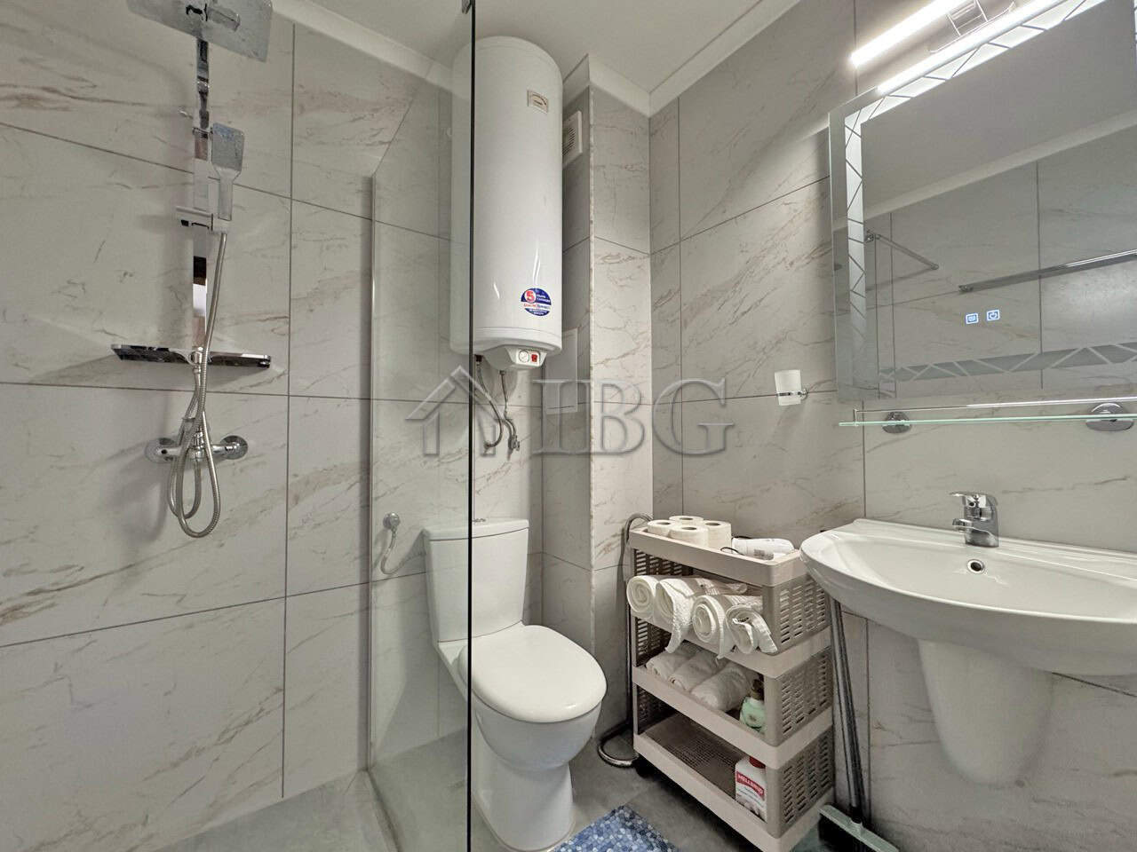 Bathroom with shower, toilet, and water heater in a spacious studio apartment.