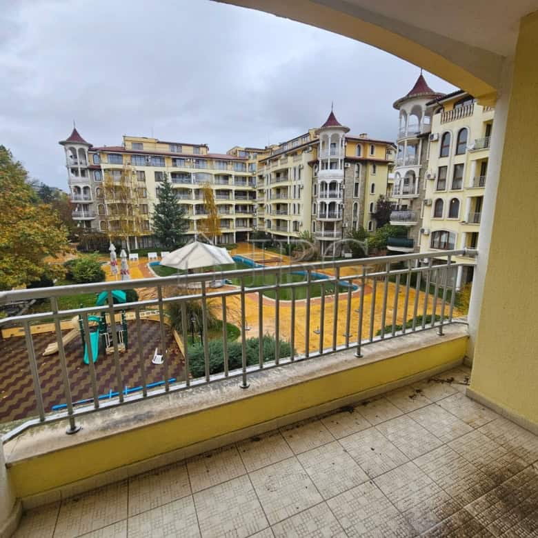 Balcony view of a two-bedroom apartment overlooking a swimming pool and residential complex.