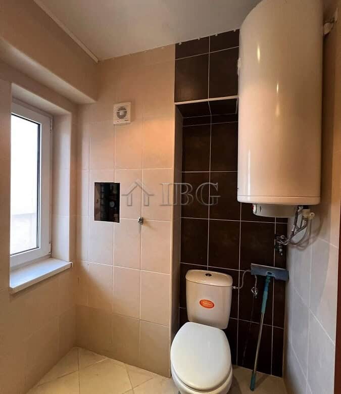 Compact bathroom featuring a water heater and a window for natural light. Ideal for modern homes in.