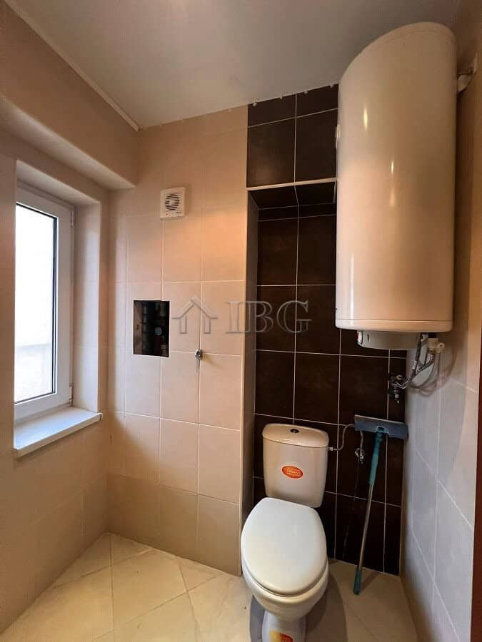 Compact bathroom featuring a water heater and a window for natural light. Ideal for modern homes in.