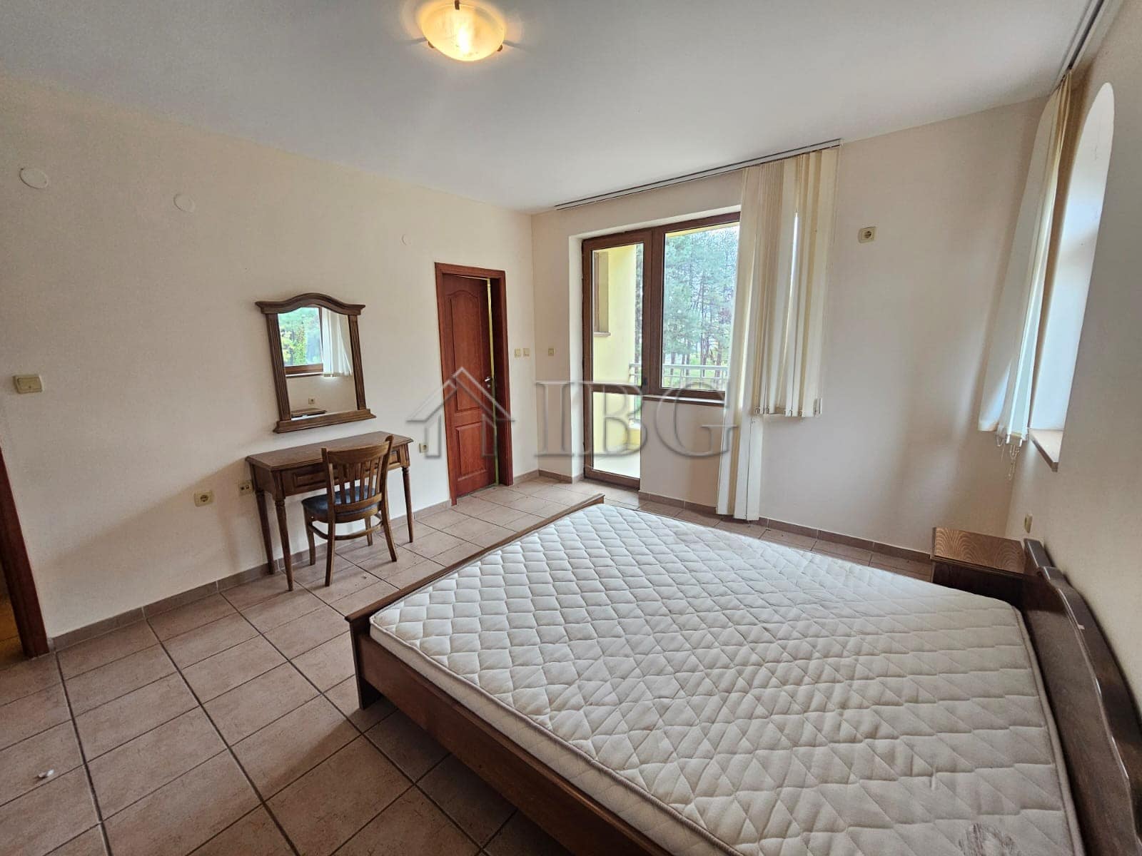 Bright bedroom with large windows overlooking the pool area.