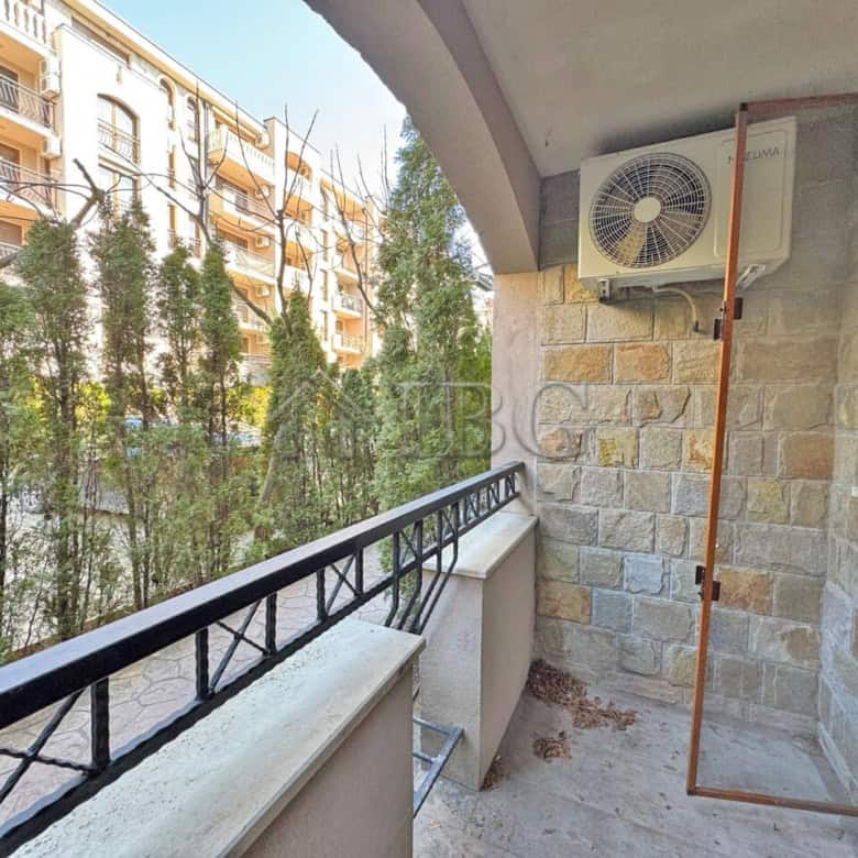 Spacious balcony view of lush greenery and neighboring buildings in Sunny Beach.