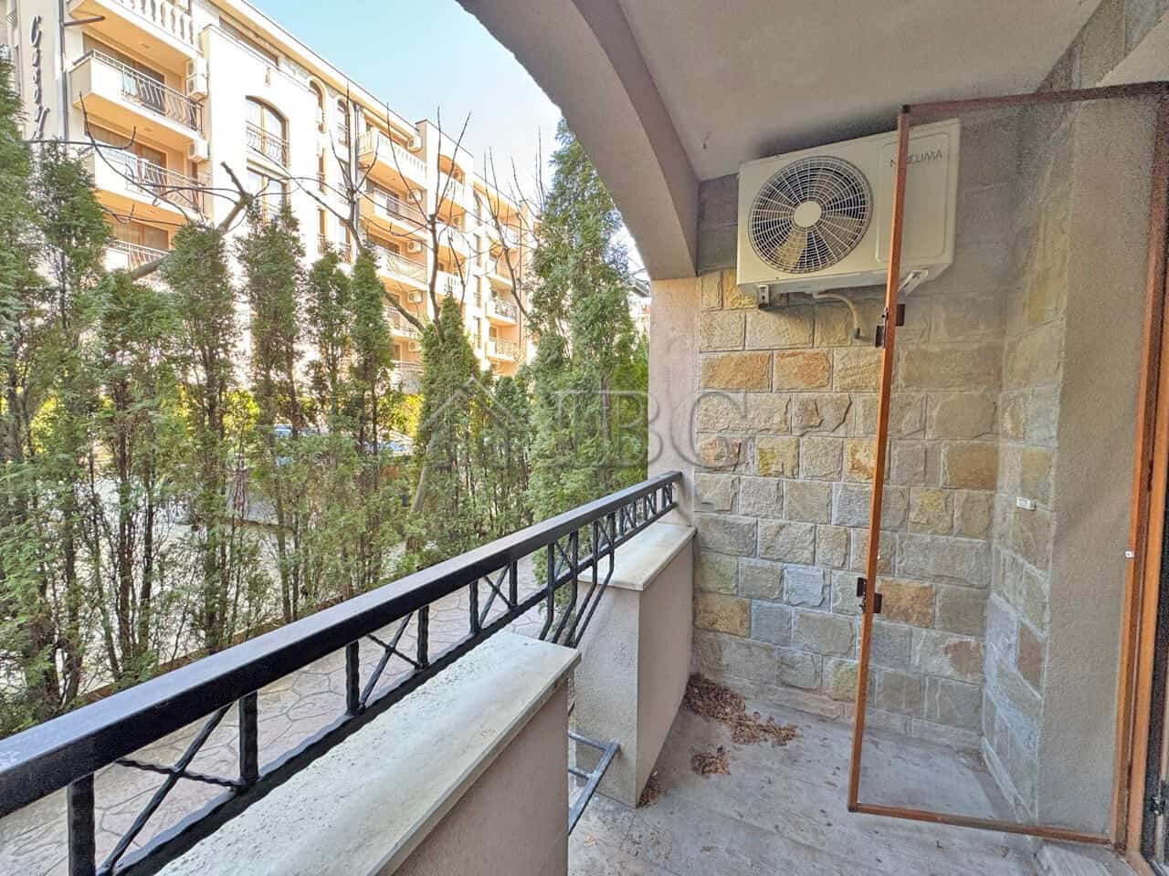 Spacious balcony view of lush greenery and neighboring buildings in Sunny Beach.