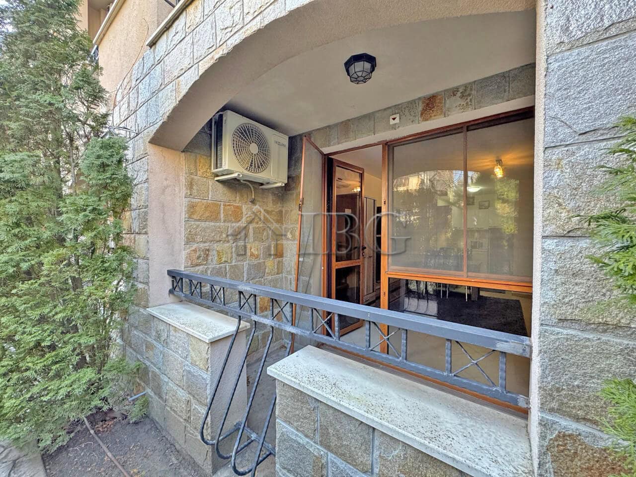 Bright 1-bedroom apartment balcony with glass doors and outdoor air conditioning unit.