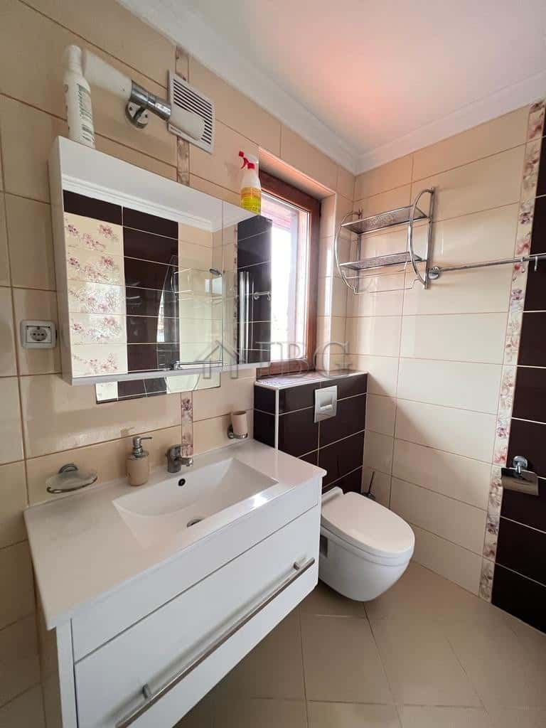 Modern bathroom with white sink and toilet in a bright apartment.