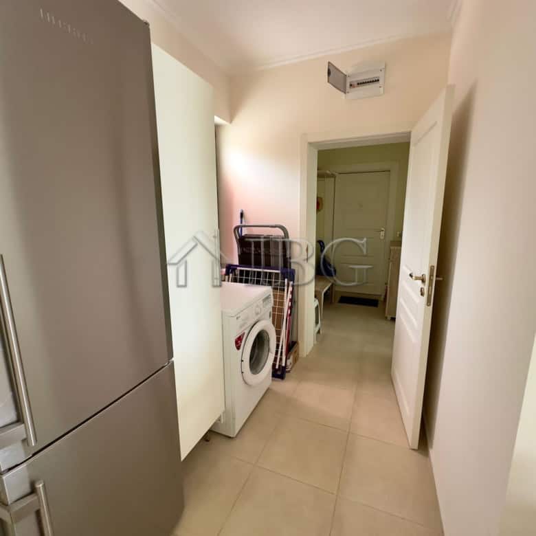 Laundry area with washing machine and storage space in a modern apartment.