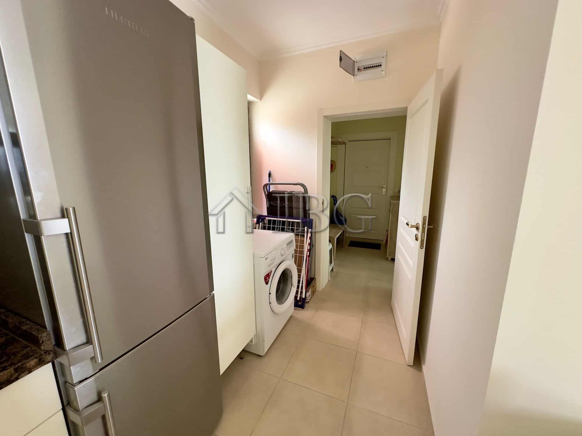 Laundry area with washing machine and storage space in a modern apartment.