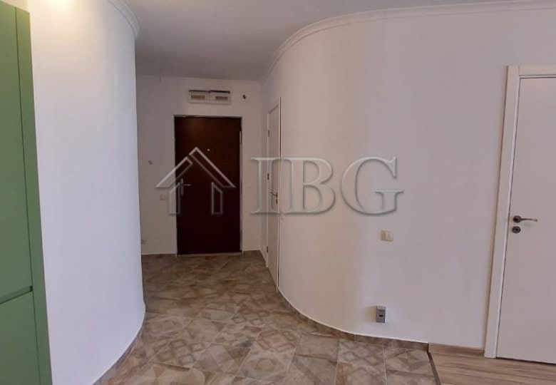 Bright interior view of a contemporary apartment entrance with white walls and wooden flooring.