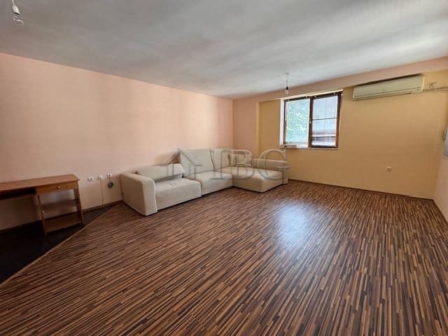 Bright living room with large windows and wooden flooring in Burgas apartment.