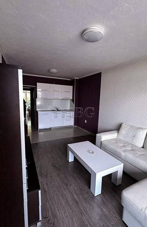 Bright living space with white sofa, coffee table, and open kitchen in Sunny Beach apartment.