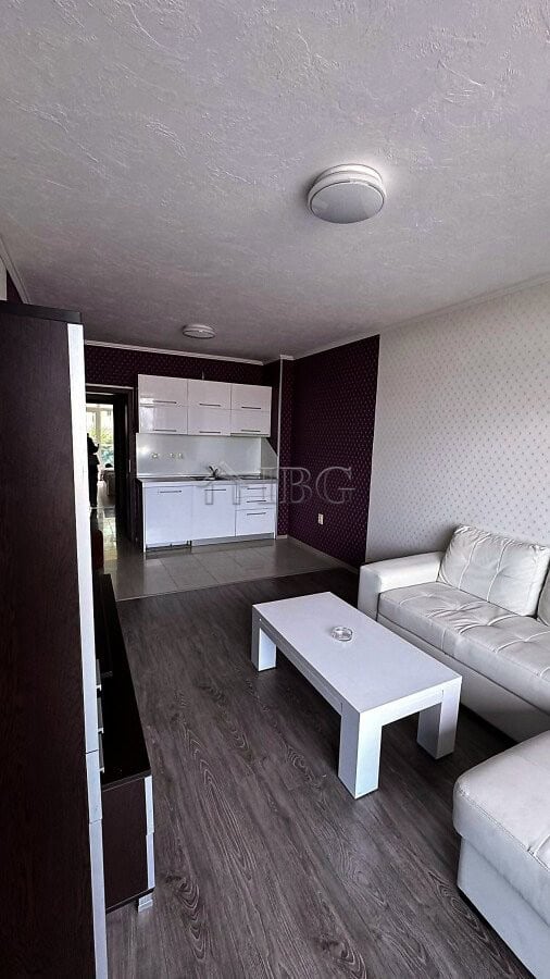 Bright living space with white sofa, coffee table, and open kitchen in Sunny Beach apartment.